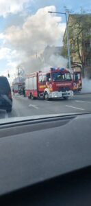 Tűzoltók oltanak egy kigyulladt dobozos járművet az Elnök utcában, sűrű füsttel borított útszakaszon.