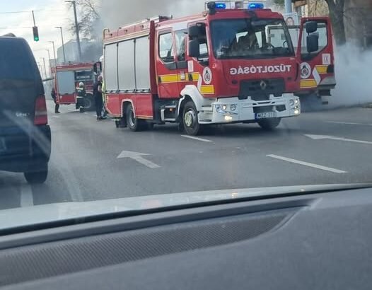 Tűzoltók oltanak egy kigyulladt dobozos járművet az Elnök utcában, sűrű füsttel borított útszakaszon.